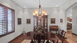 Dining space with arched walkways, recessed lighting, a chandelier, wood finished floors, and baseboards