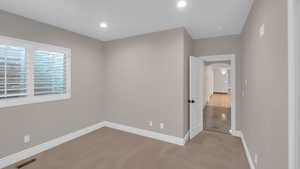 Unfurnished bedroom featuring visible vents, baseboards, arched walkways, recessed lighting, and light colored carpet