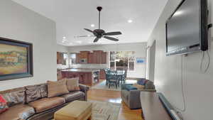 Living room with recessed lighting, a ceiling fan, light wood-style floors, and a healthy amount of sunlight