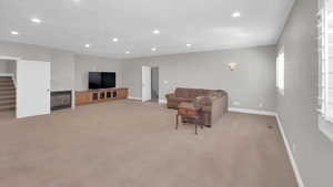 Living room with baseboards, recessed lighting, a glass covered fireplace, and light carpet