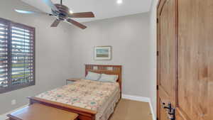 Bedroom featuring baseboards, a ceiling fan, and light carpet