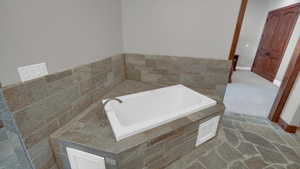 Bathroom featuring a bath, baseboards, and visible vents
