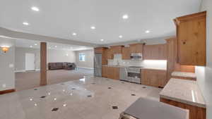 Kitchen featuring baseboards, recessed lighting, open floor plan, light tile patterned flooring, and appliances with stainless steel finishes