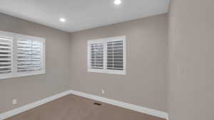 Carpeted empty room featuring recessed lighting, visible vents, and baseboards