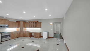 Kitchen featuring glass insert cabinets, baseboards, arched walkways, appliances with stainless steel finishes, and recessed lighting
