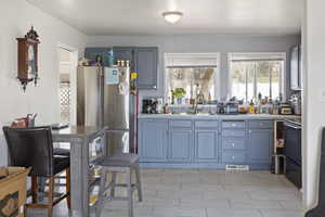 Kitchen featuring visible vents, a sink, freestanding refrigerator, range, and tile countertops