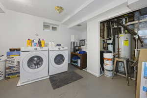 Laundry area with laundry area, washing machine and clothes dryer, gas water heater, and a textured ceiling