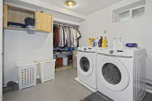 Clothes washing area featuring cabinet space, washing machine and dryer, and a textured ceiling