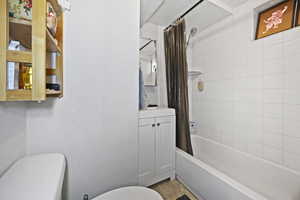 Full bath featuring toilet, vanity, and shower / bath combination with curtain