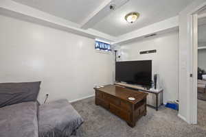 Carpeted living area with visible vents, baseboards, and a textured ceiling