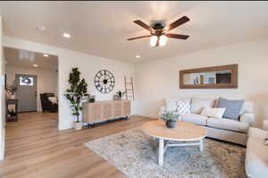 Living room with light wood-style flooring, recessed lighting, ceiling fan, and baseboards