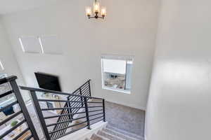 Stairway featuring a chandelier, baseboards, and carpet