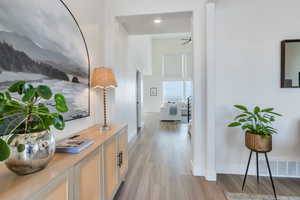 Hallway featuring a towering ceiling, visible vents, baseboards, and wood finished floors