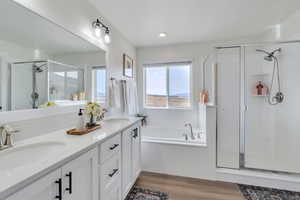 Bathroom with a shower stall, a bath, a sink, and wood finished floors