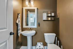 Half bathroom featuring an inviting chandelier and toilet
