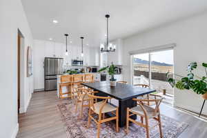 Dining space featuring baseboards, a mountain view, a chandelier, recessed lighting, and light wood-style flooring