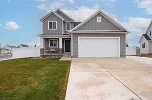 Craftsman-style house featuring board and batten siding, covered porch, fence, a front lawn, and concrete driveway