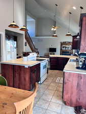 Kitchen with light tile patterned floors, light countertops, a ceiling fan, white appliances, and high vaulted ceiling