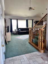 Carpeted living area with a ceiling fan, stone finish flooring, and stairs