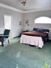 Carpeted bedroom with ornamental molding and a wainscoted wall
