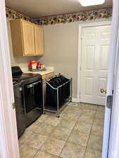 Laundry room featuring cabinet space, light tile patterned floors, and separate washer and dryer
