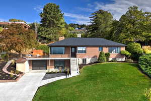 View of front of property with stairs, brick siding, driveway, a chimney, and a front yard
