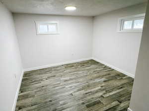 Empty room with baseboards, wood finished floors, and a textured ceiling