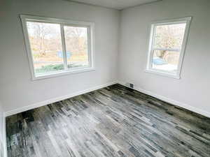 Empty room with visible vents, wood finished floors, and a healthy amount of sunlight