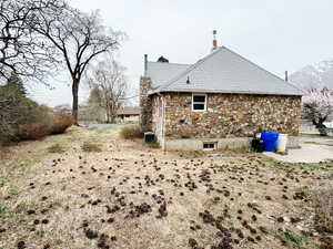 View of side of home with cooling unit, a chimney, and stone siding