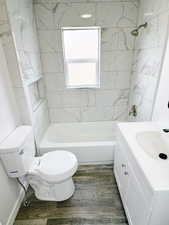Bathroom with vanity,  shower combination, toilet, and wood finished floors