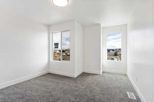 Spare room featuring carpet flooring, baseboards, and visible vents