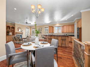 Dining space with recessed lighting, a fireplace, crown molding, ceiling fan with notable chandelier, and wood finished floors