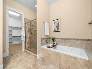 Full bathroom with a shower stall, a bath, tile patterned flooring, and a walk in closet