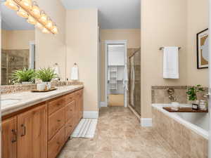 Full bathroom with a sink, a bath, a shower stall, and double vanity