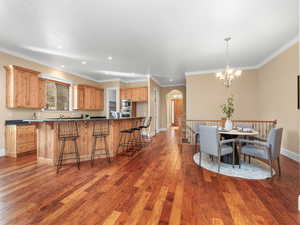 Dining area with a chandelier, arched walkways, dark wood-style floors, and baseboards