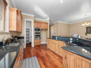 Kitchen featuring arched walkways, ornamental molding, wood finished floors, a sink, and stainless steel appliances