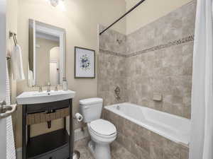 Guest bathroom with toilet, tiled shower / bath, vanity, and tile patterned flooring