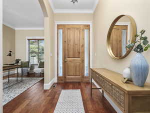 Entryway with dark wood-type flooring and ornamental molding