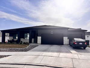 View of front of property featuring an attached garage, stone siding, and concrete driveway