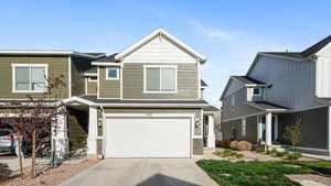 View of front of house with an attached garage, stone siding, and driveway