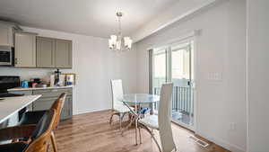 Dining room with baseboards, an inviting chandelier, light wood-style flooring, a textured ceiling, and visible vents