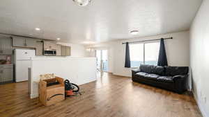 Living area featuring a chandelier, a textured ceiling, wood finished floors, and baseboards