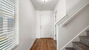 Doorway featuring light wood-type flooring, a healthy amount of sunlight, a textured ceiling, and stairway