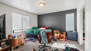 Carpeted bedroom with visible vents, a textured ceiling, and baseboards