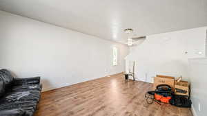 Living area featuring light wood-style flooring, a textured ceiling, and baseboards