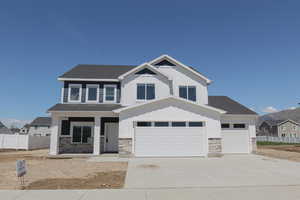 Craftsman inspired home featuring a porch, fence, stone siding, concrete driveway, and board and batten siding