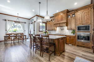 Kitchen with oven, black microwave, light countertops, brown cabinets, and cooktop