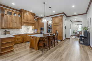 Kitchen featuring stainless steel oven, black microwave, stovetop, light countertops, and light wood-style floors