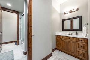 Full bathroom featuring marble finish flooring, vanity, and combined bath / shower with glass door
