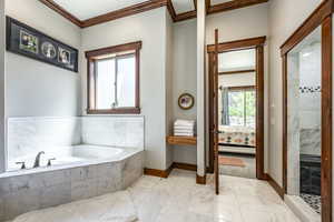 Bathroom featuring ornamental molding, a garden tub, ensuite bath, marble finish floors, and a shower